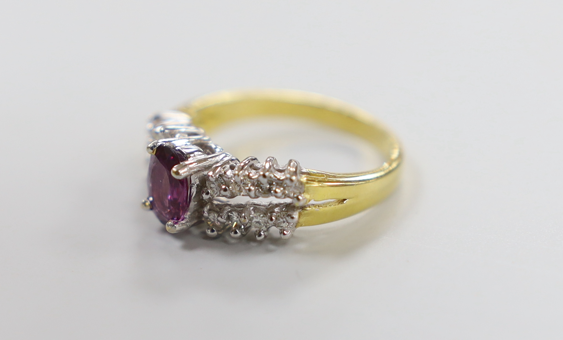A modern 18ct gold and single stone oval cut garnet? dress ring, with two row diamond set shoulders, size N, gross weight 5.2 grams.